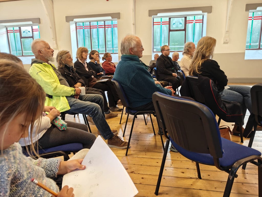 3 rows of audience members on chairs in a semi circle